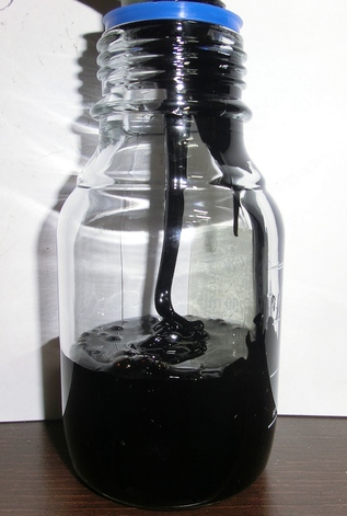 A thick black liquid being poured into in a bottle