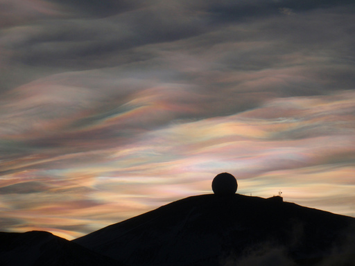 Colourful, wispy clouds above a silhouette of a radome